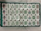 Classic white mahjong tiles with forest green backs on felt
